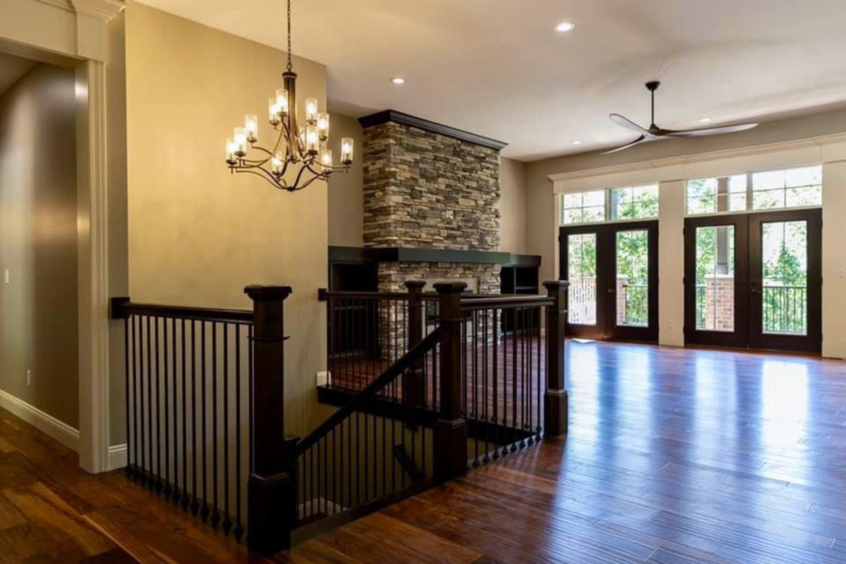 A Superior Homes custom build in the Metro East: the living area beneath a wrought-iron chandelier, with a stacked-stone fireplace and dark walnut floors