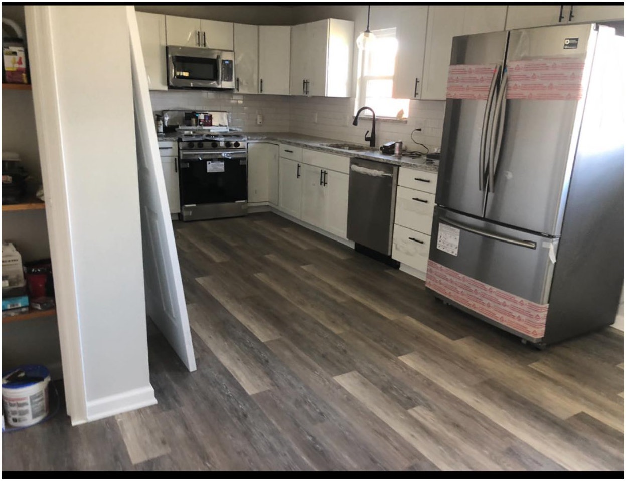 A Granite City kitchen with new white cabinets, stainless appliances and plank flooring, photographed before furnishing